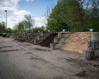 Verschiedene Kompost- und Mulchmaterialien in betonierten Stellflächen mit Schaufeln